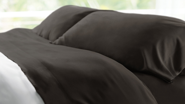 Luxurious dark brown bedding set with elegant pillows and cozy ambiance.