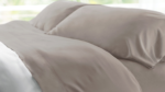 Cream duvet and taupe pillows in a serene, light-filled bedroom for relaxation.