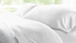 Luxurious white bedding with plush pillows in tranquil, natural light.