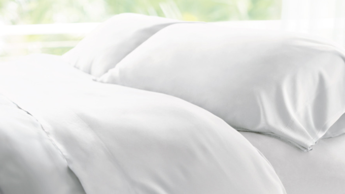 Luxurious white bedding with plush pillows in tranquil, natural light.