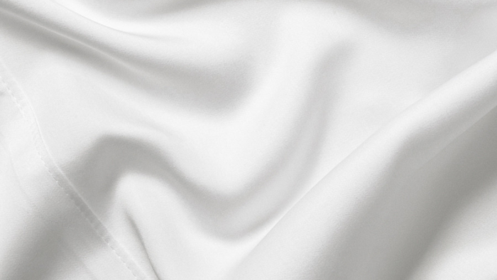 Luxurious white fabric draped elegantly, highlighting its silky sheen and sophisticated texture.