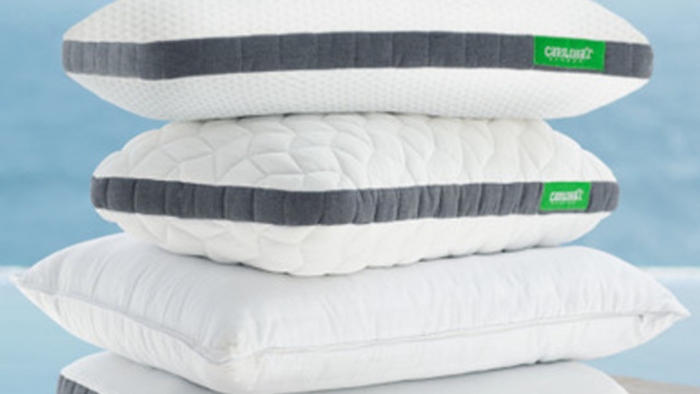 Stack of quilted pillows with unique textures against a serene coastal backdrop for ultimate comfort.