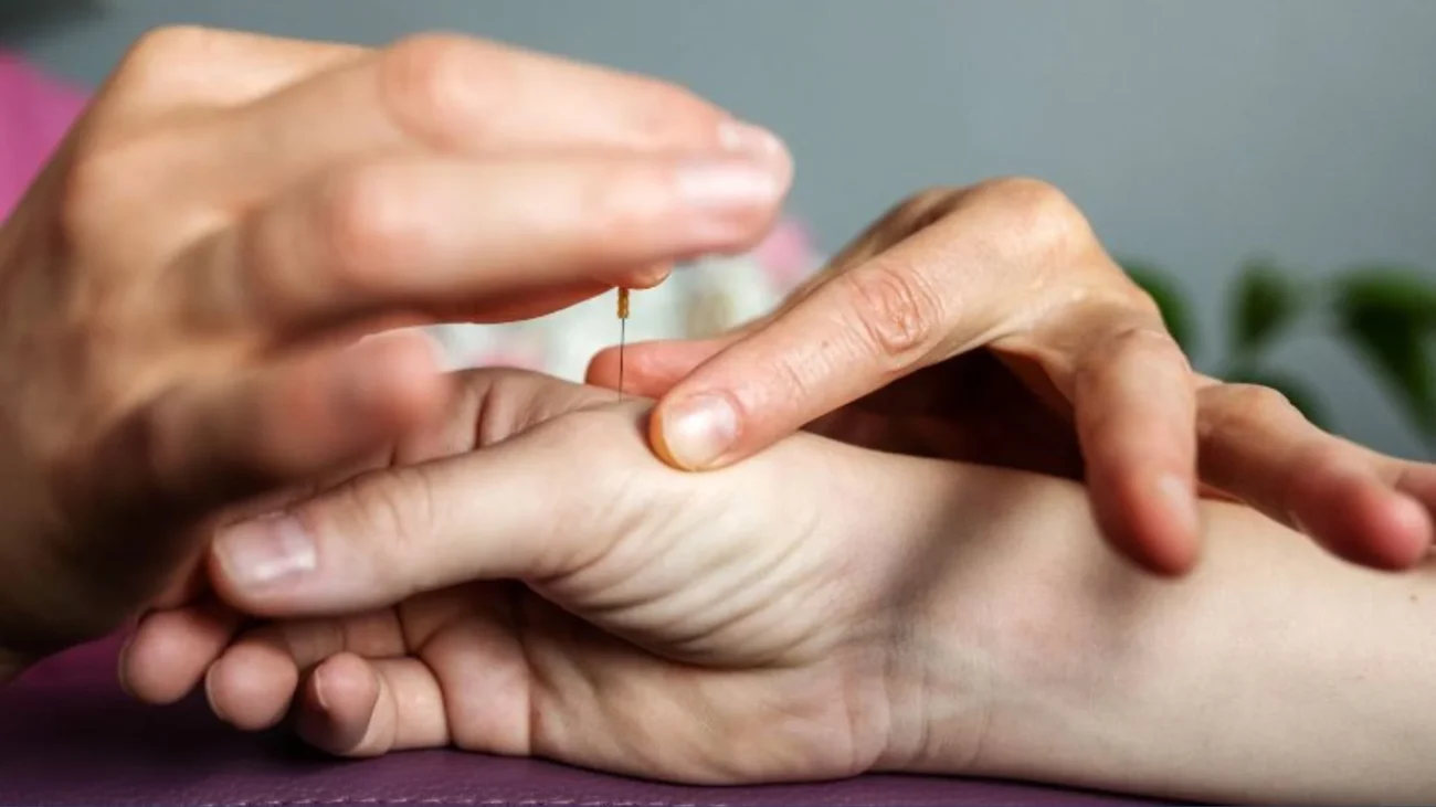 Close-up of acupuncture needle insertion into wrist, highlighting serene therapeutic ambiance.