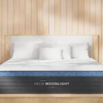 Modern bedroom with Helix Moonlight mattress, light wood accents, plush bedding, and arched mirrors.