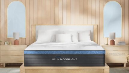 Modern bedroom with Helix Moonlight mattress, light wood accents, plush bedding, and arched mirrors.