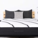 Modern bedroom with LOFT Firm Hybrid mattress, gray pillows, wooden bed, and nightstands.