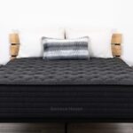 Modern bedroom with CHALET Luxe Firm mattress, geometric pillows, and sleek black furniture.