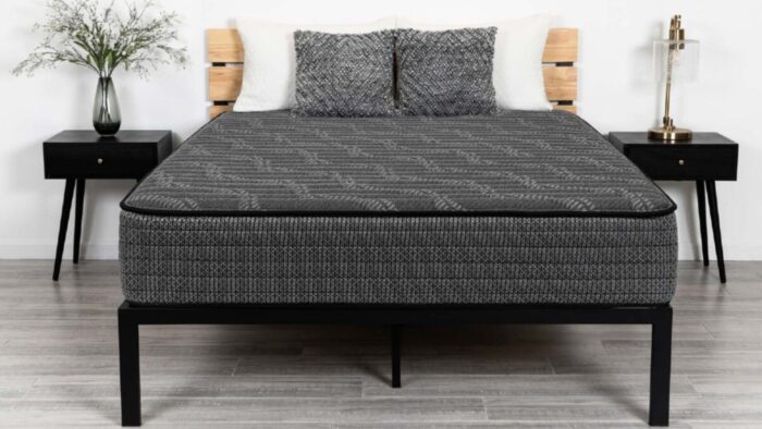 Modern bedroom with geometric mattress, minimalist nightstands, warm lamps, and light wooden floors.