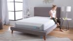 Young woman reading in a serene, modern bedroom with gray upholstered bed.