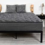 Modern bedroom with gray mattress, black frame, stylish pillows, and elegant nightstands.