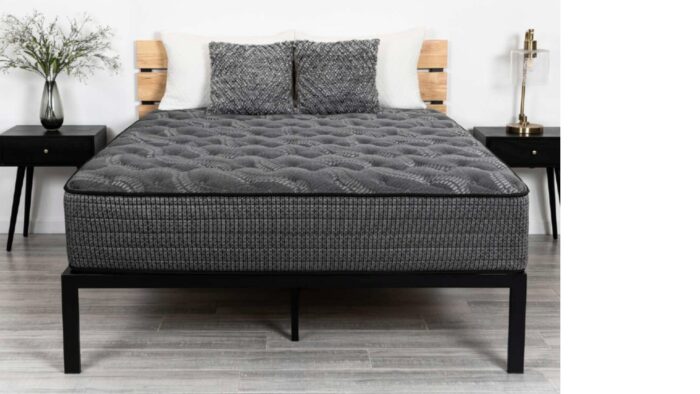 Modern bedroom with gray mattress, black frame, stylish pillows, and elegant nightstands.