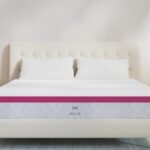 Modern bedroom with cream headboard, gray mattress, pink accents, and wood furniture.