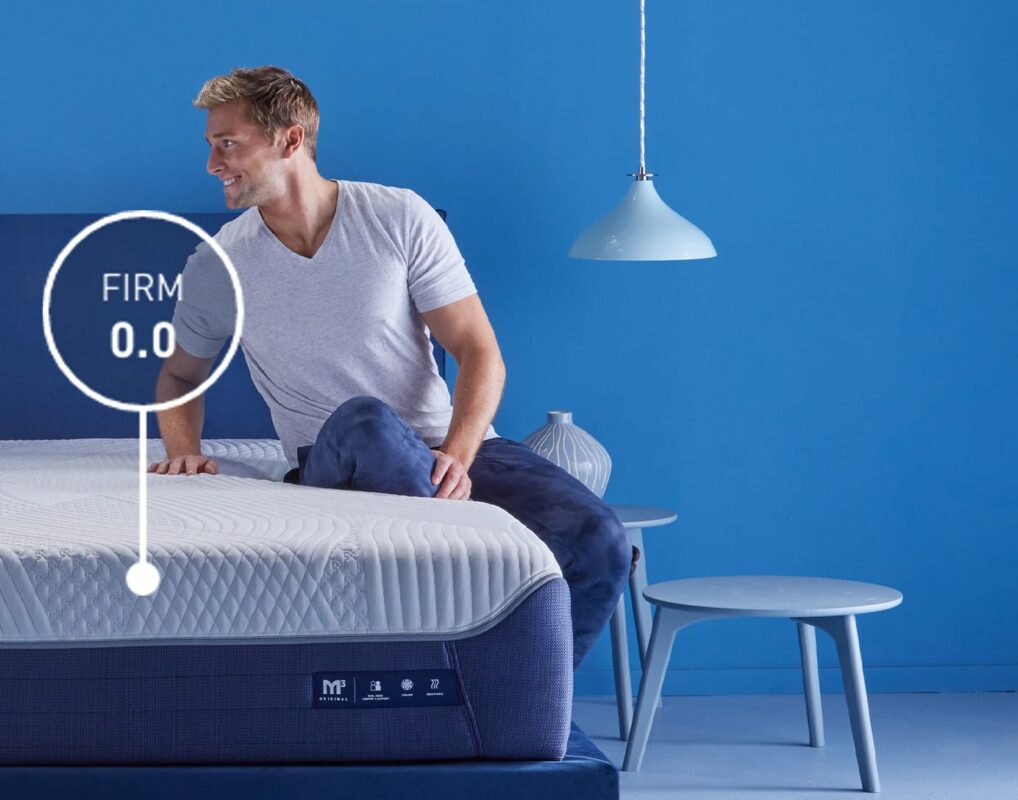 Modern mattress in vibrant room with relaxed man showcasing adjustable firmness feature.