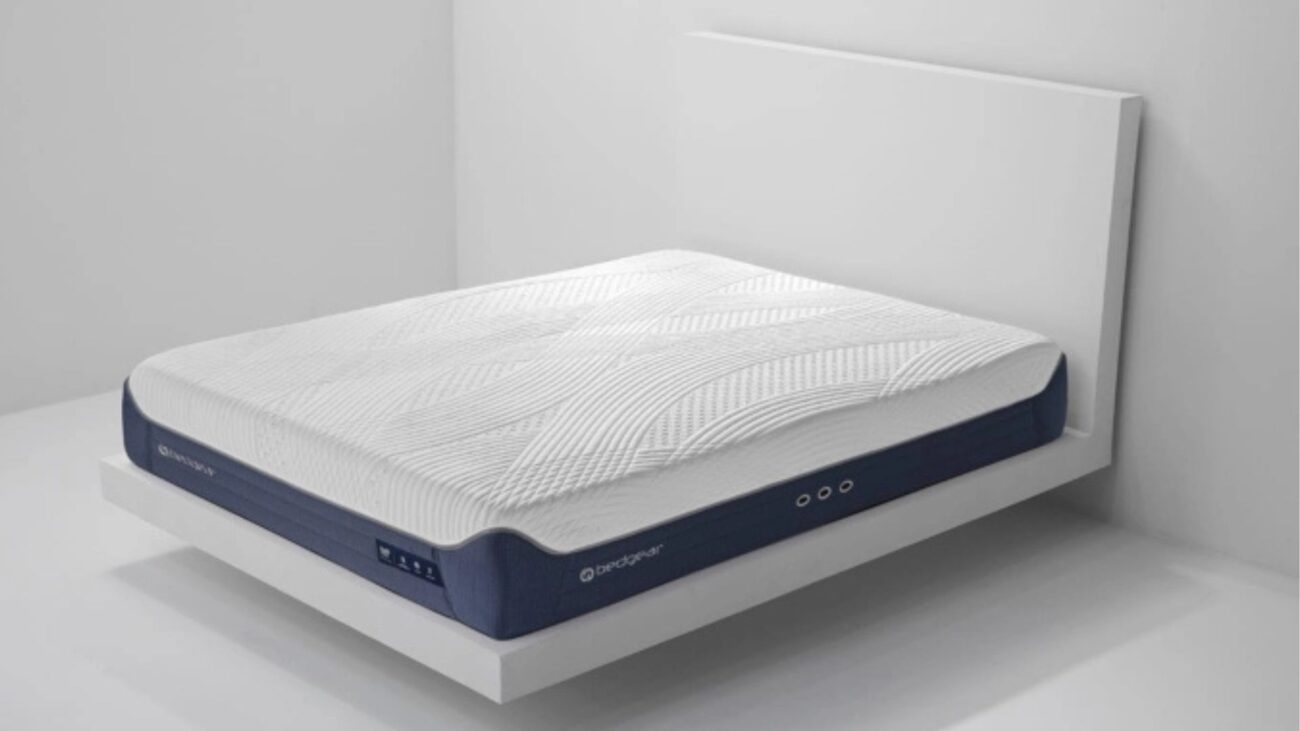 Modern ergonomic mattress on minimalist wooden frame against white wall for serene bedroom.