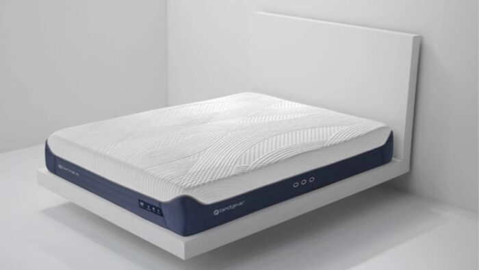 Modern ergonomic mattress on minimalist wooden frame against white wall for serene bedroom.