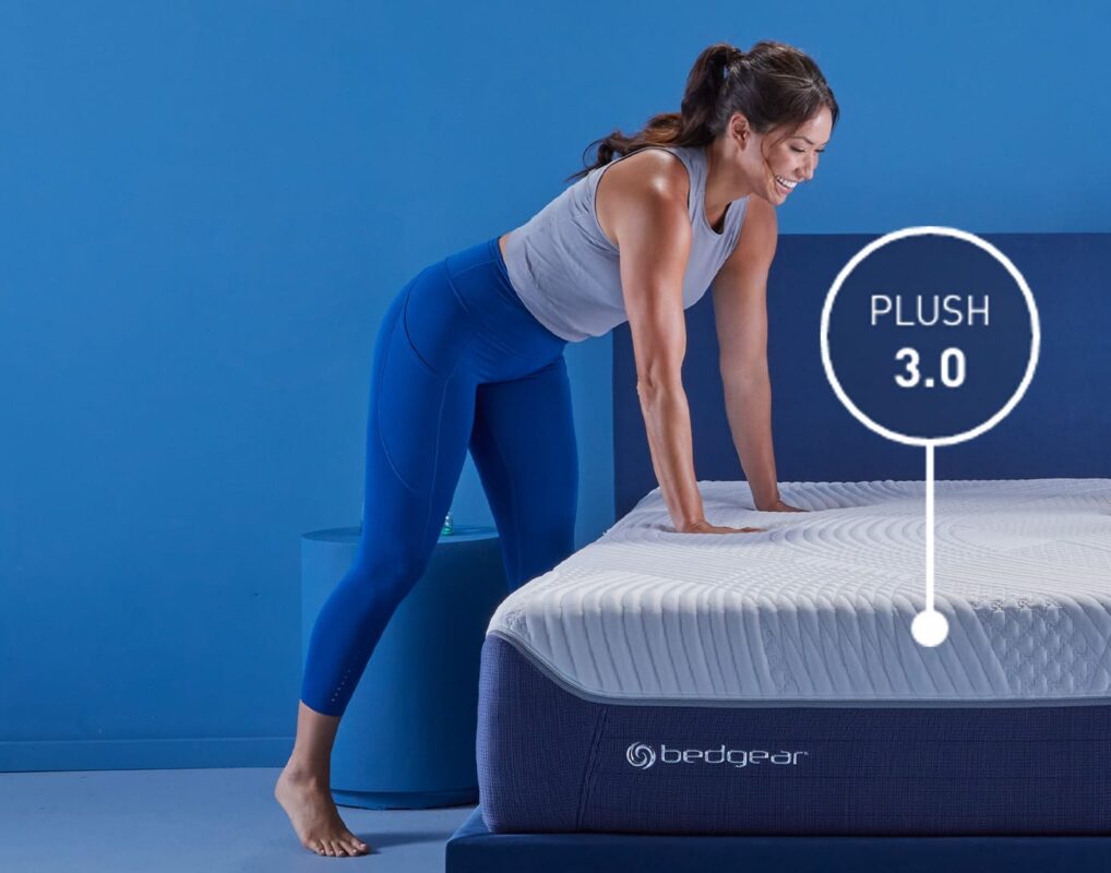 Young woman explores Bedgear Plush 3.0 mattress for comfort in modern, vibrant setting.