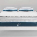 Modern minimalist bedroom with X-1 mattress, blue accents, cozy bedding, and bedside lamp.