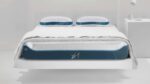 Modern minimalist bedroom with X-1 mattress, blue accents, cozy bedding, and bedside lamp.