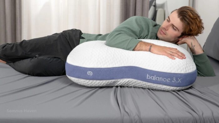 Young man relaxes on a bed with ergonomic Balance 3.X pillow in serene setting.