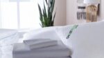 Tranquil bedroom with plush bedding, GhostPillow, greenery, and warm lighting. Ideal sleep sanctuary.