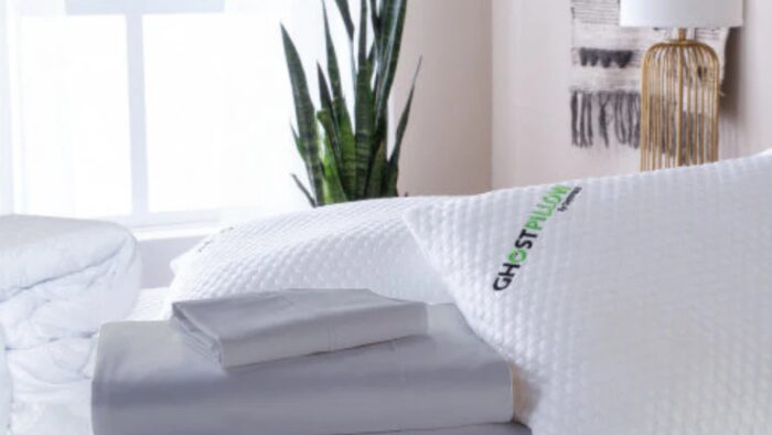 Tranquil bedroom with plush bedding, GhostPillow, greenery, and warm lighting. Ideal sleep sanctuary.