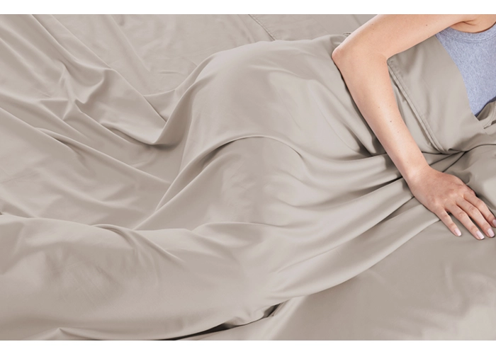 Person relaxing under a silky beige blanket, showcasing comfort and serenity.