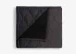 Elegant quilted black throw blanket with sherpa lining, ideal for warmth and modern decor.