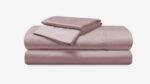 Luxurious blush-pink bedding set with satin sheen, including sheets and pillowcases for elegant comfort.