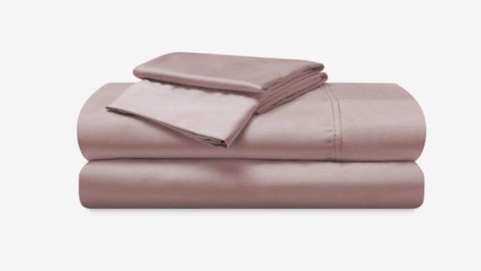 Luxurious blush-pink bedding set with satin sheen, including sheets and pillowcases for elegant comfort.