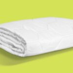 White comforter with quilting on lime green background, highlighting modern design and craftsmanship.