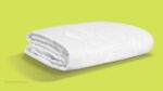 White comforter with quilting on lime green background, highlighting modern design and craftsmanship.