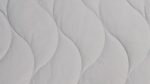 Light gray quilted mattress topper with wave pattern for comfort and airflow.