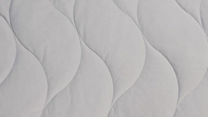 Light gray quilted mattress topper with wave pattern for comfort and airflow.
