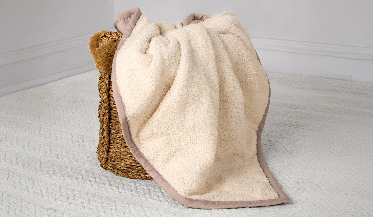 Cozy rustic basket with plush cream blanket, ideal for cozy home relaxation.