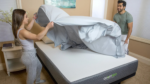 Couple making bed in cozy bedroom with sleek modern mattress.
