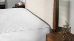 Minimalist bedroom with textured mattress cover, upholstered headboard, and dark wood nightstands.