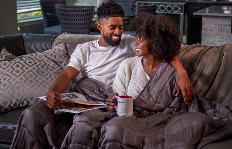 Cozy couple on couch with warm decor and shared joyful moment.