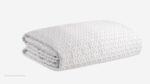 Plush white blanket with interlocking textured pattern, ideal for warmth and home decor.