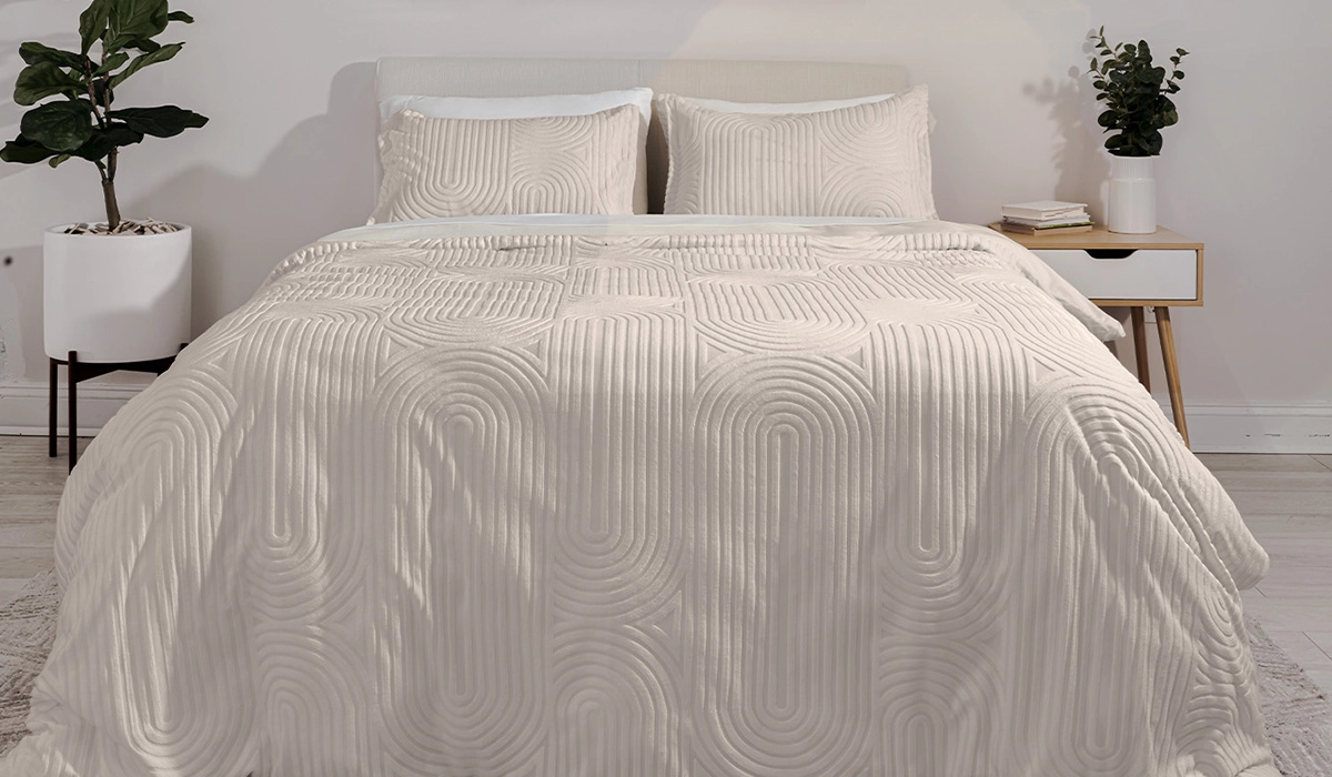 Serene cream bedroom with soft textures, matching pillows, minimal nightstand, and natural light.