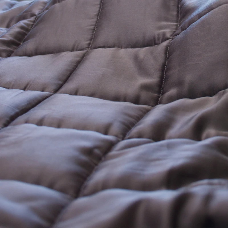 Luxurious brown quilted blanket with plush texture and elegant stitching pattern.