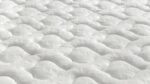 Close-up of white quilted mattress with wave-like texture, enhancing comfort and airflow.