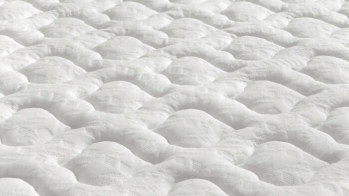 Close-up of white quilted mattress with wave-like texture, enhancing comfort and airflow.