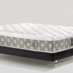 Plush white mattress with geometric sides on sleek black platform bed frame with metallic legs.