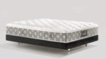 Plush white mattress with geometric sides on sleek black platform bed frame with metallic legs.