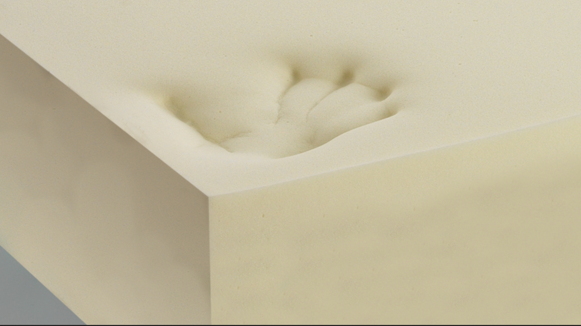 Close-up of cream foam with an indentation, highlighting texture and resilience for comfort use.