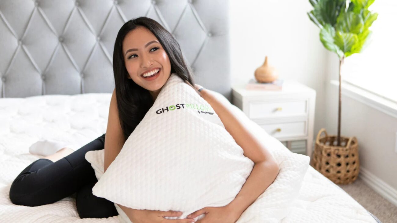 Woman relaxing with GhostPillow in plush bedroom, exuding comfort, elegance, and serenity.
