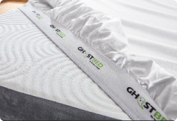 GhostBed mattress with plush surface, padded edge, and green-accented logo for comfort and freshness.