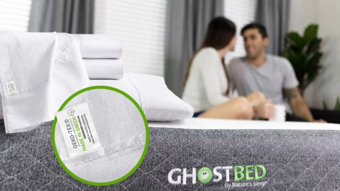 Modern bedroom with GhostBed mattress, eco-friendly sheets, and couple talking in sunlight.