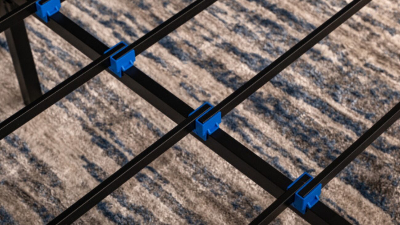 Modern black metal bed frame with blue connectors, on a blue-gray patterned rug.
