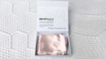 Blush pink GhostBed silk pillowcase in minimalistic packaging for luxurious sleep experience.